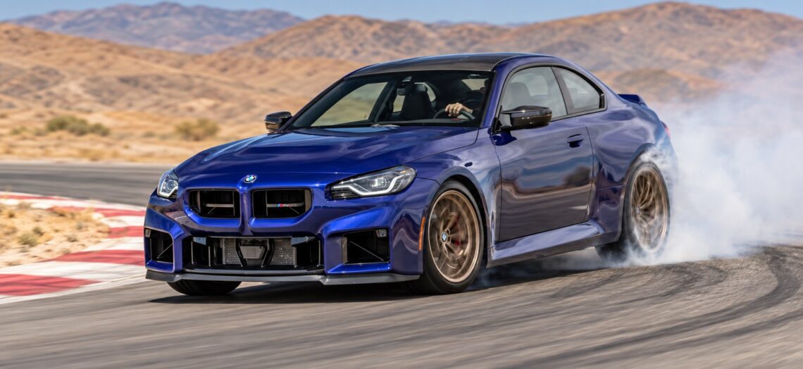 Blue BMW M2 CS coupe powering out of a corner on a racetrack